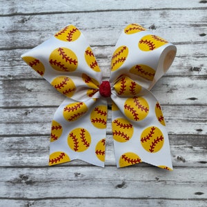 May include: White softball hair bow with yellow and red softball print.