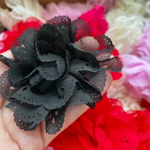 May include: A black lace flower with a delicate, ruffled design. The flower is made of soft, sheer fabric and has a vintage aesthetic.