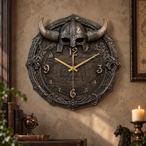 Könnte beinhalten: Eine runde Wanduhr mit dunkler, verwitterter Oberfläche und einem integrierten dreidimensionalen Wikingerhelm an der Oberseite. Das Zifferblatt zeigt erhabene metallische Ziffern 3, 4, 5, 6, 7, 8, 9, 10 und 12 sowie dünne goldfarbene Zeiger.