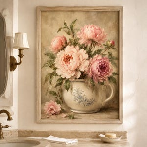 May include: A framed wall art print depicting a bouquet of soft pink peonies arranged in a cream-colored ceramic pitcher with a blue floral pattern. The painting features lush green leaves and stems, set against a muted, neutral-toned background.