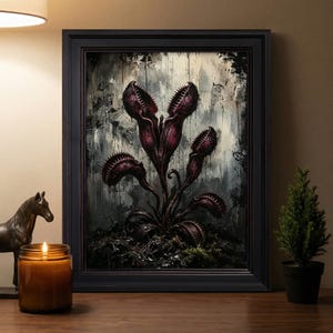 May include: A framed wall art print featuring a dark, moody illustration of a carnivorous plant with multiple open, toothy traps in shades of deep purple and black, set against a distressed, textured background with vertical paint drips.