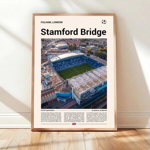 May include: A framed poster featuring an aerial photograph of Stamford Bridge stadium in Fulham, London. The print includes the text 'Stamford Bridge', 'Fulham, London', a small soccer ball icon, capacity details, and descriptive text blocks.
