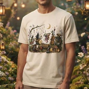 Op de afbeelding: Een crèmekleurig T-shirt met korte mouwen en een gedetailleerde grafische print van diverse insecten die op een boomstam muziekinstrumenten bespelen, waaronder een kever op drums en een nachtvlinder op een cello.