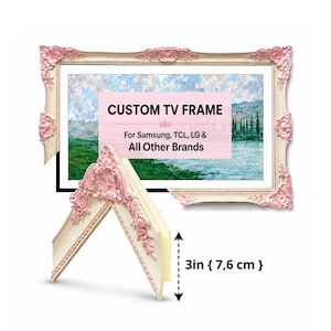 Op de afbeelding: Een decoratieve tv-lijst met een gebroken witte basis en roze, sierlijke bloemaccenten. De lijst omringt een landschapsschilderij en bevat de tekst CUSTOM TV FRAME For Samsung, TCL, LG & All Other Brands. Een hoekmonster toont een hoogte van 7,6 cm.