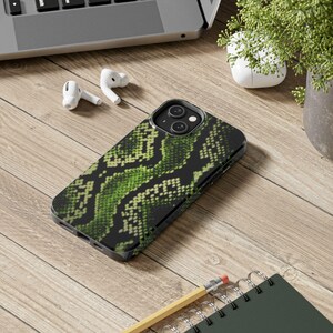May include: A smartphone case featuring a vibrant green and black snakeskin pattern. The case has a dual-camera cutout on the back and covers the rear and sides of the device, showcasing a detailed reptilian scale texture in shades of lime.