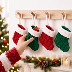 May include: Four small Christmas stockings hanging from a wooden rack. Two stockings are red and two are green, all featuring a white knitted cuff and a cable knit texture. One green stocking contains a small red gift box with a gold ribbon.
