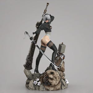 May include: A detailed collectible figure of a character with short white hair, wearing a black outfit, a blindfold, and thigh-high boots. The figure holds a large sword and stands on a rocky base with small white flowers and a mechanical companion.