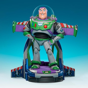 Puede incluir: Una figura de acción de Buzz Lightyear de pie sobre una base con alas extendidas de color morado y verde. La figura viste un traje espacial blanco, verde y morado con un casco transparente, con el texto SPACE RANGER y LIGHTYEAR en el pecho.