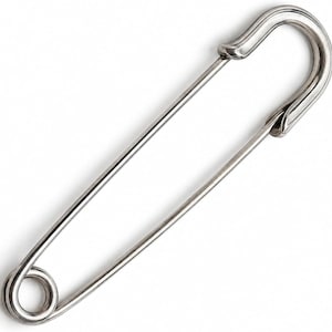 May include: A large, silver-toned metal safety pin featuring a classic coiled spring mechanism at one end and a secure clasp closure at the other. The pin is constructed from a single piece of polished wire, bent into an elongated shape.