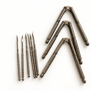 May include: A set of three silver-toned metal nutcrackers with textured, ridged handles and six matching metal picks with pointed, curved tips. Each tool features a consistent metallic finish and a detailed, cross-hatched grip pattern throughout.