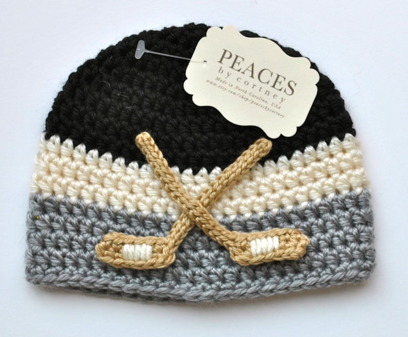 Black, gray, and white stripe baby hat with hockey sticks appliques.