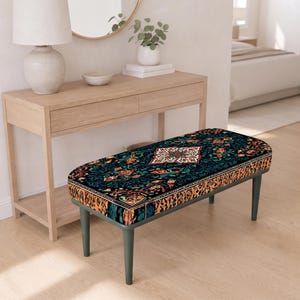 May include: A rectangular bench featuring a dark teal and black upholstery with a detailed floral and geometric pattern. The bench is supported by four tapered dark gray legs, providing a stable base for the cushioned seat top.