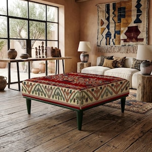 Puede incluir: Un otomán cuadrado con una superficie superior de color rojo intenso con un patrón geométrico multicolor y un panel lateral de color crema adornado con un motivo repetitivo en verde, naranja y azul. Se apoya sobre cuatro patas cónicas verde oscuro.