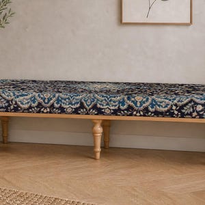 May include: A long rectangular bench featuring a dark blue and cream patterned fabric upholstery with a detailed floral motif. The bench is supported by six light-colored wooden legs with a turned, spindle-style design and a smooth finish.