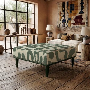 Può includere: Un pouf quadrato caratterizzato da una stampa leopardata color crema e verde scuro. Il mobile è sostenuto da quattro gambe affusolate color verde scuro e presenta una silhouette bassa e squadrata con bordi dritti e una superficie superiore piatta e imbottita.