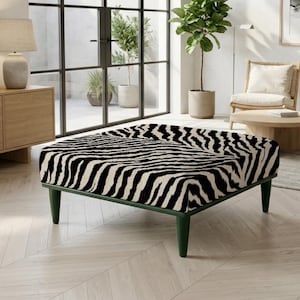Pode incluir: Um otomano quadrado com um padrão de riscas de zebra a preto e branco na almofada superior, apoiado por quatro pernas cónicas verde-escuras. A peça tem um design de perfil baixo com uma superfície plana almofadada e uma estrutura.