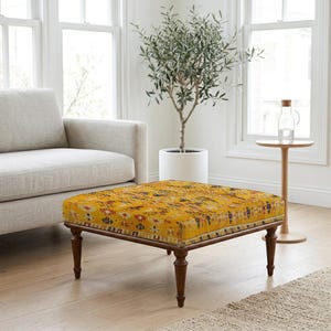 Può includere: Un pouf quadrato rivestito in un vivace tessuto giallo senape con un motivo geometrico e floreale multicolore. Il mobile è sostenuto da quattro gambe in legno marrone scuro dal design tornito, che offrono una base stabile alla seduta.