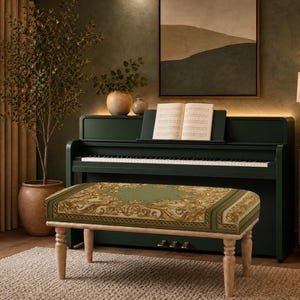 May include: A rectangular piano bench with four light-colored wooden legs and a cushioned seat featuring a green and gold ornate pattern. The bench is positioned in front of a dark green upright piano with an open music book on the music stand.