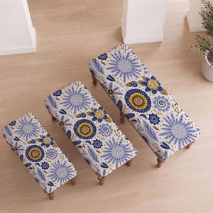 May include: Three rectangular benches of varying lengths, each featuring a white fabric upholstery with a repeating pattern of blue, dark blue, and mustard yellow floral and leaf motifs, supported by four short, turned wooden legs.