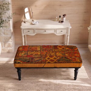 May include: A rectangular ottoman featuring a vibrant patchwork upholstery with intricate patterns in shades of red, orange, yellow, and black. The piece is supported by four dark, turned wooden legs, providing a stable base for the cushioned top.