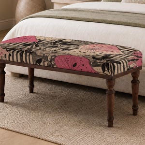 May include: A rectangular upholstered bench featuring four dark brown turned wooden legs. The seat cushion is covered in a fabric with a bold pattern of large pink lotus-like flowers, black foliage, and dark stripes on a light beige background.