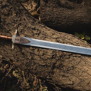 May include: A double-edged sword featuring a metallic silver blade with a geometric pattern, a copper-toned handle, and a crossguard adorned with a triangular emblem containing a trident-like symbol in a bronze finish.