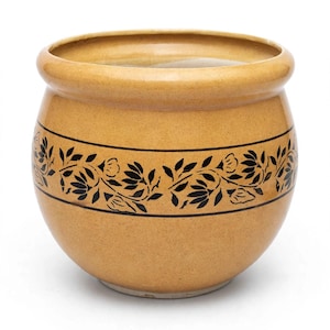 May include: A round, mustard-yellow ceramic planter with a wide, rolled rim. The exterior features a horizontal band decorated with a black, repeating floral and leaf pattern enclosed by two thin black lines encircling the center of the pot.