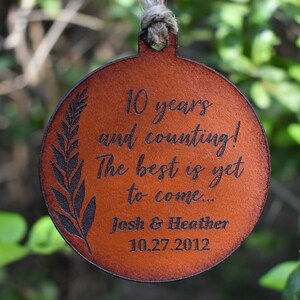 May include: A brown leather ornament with the text "10 years and counting! The best is yet to come... Josh & Heather 10.27.2012" engraved on it.