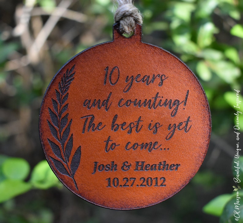 May include: A brown leather ornament with the text "10 years and counting! The best is yet to come... Josh & Heather 10.27.2012" engraved on it.