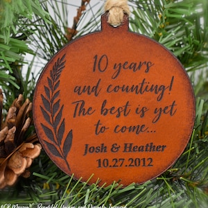 May include: A brown leather ornament with the text "10 years and counting! The best is yet to come... Josh & Heather 10.27.2012" engraved on it.