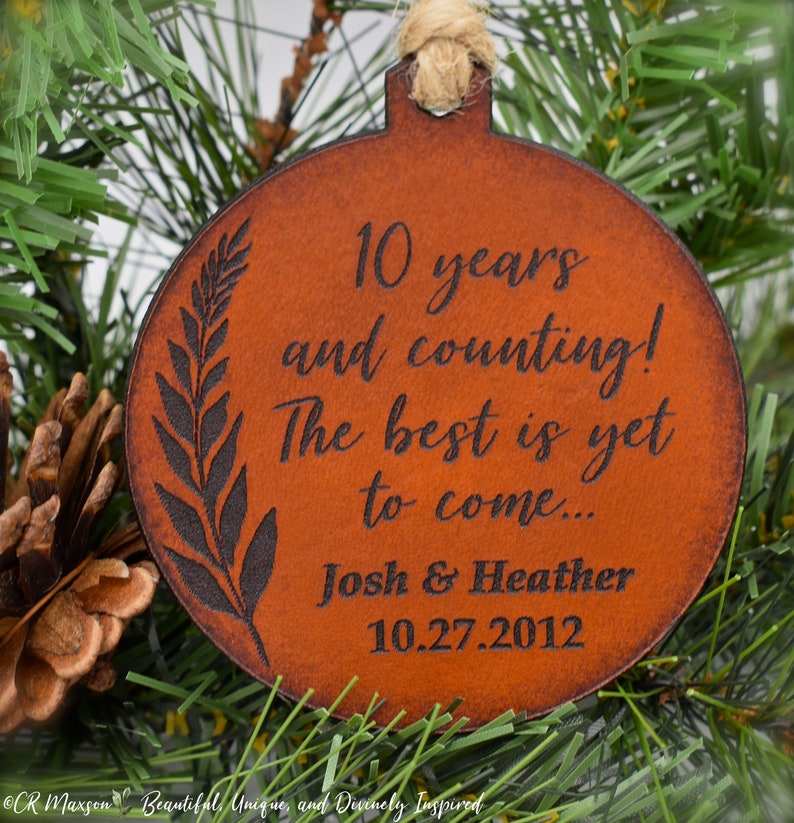May include: A brown leather ornament with the text "10 years and counting! The best is yet to come... Josh & Heather 10.27.2012" engraved on it.
