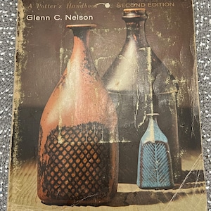 May include: A book titled "Ceramics: A Potter's Handbook, Second Edition" by Glenn C. Nelson. The cover features three ceramic vases in different colors and styles.