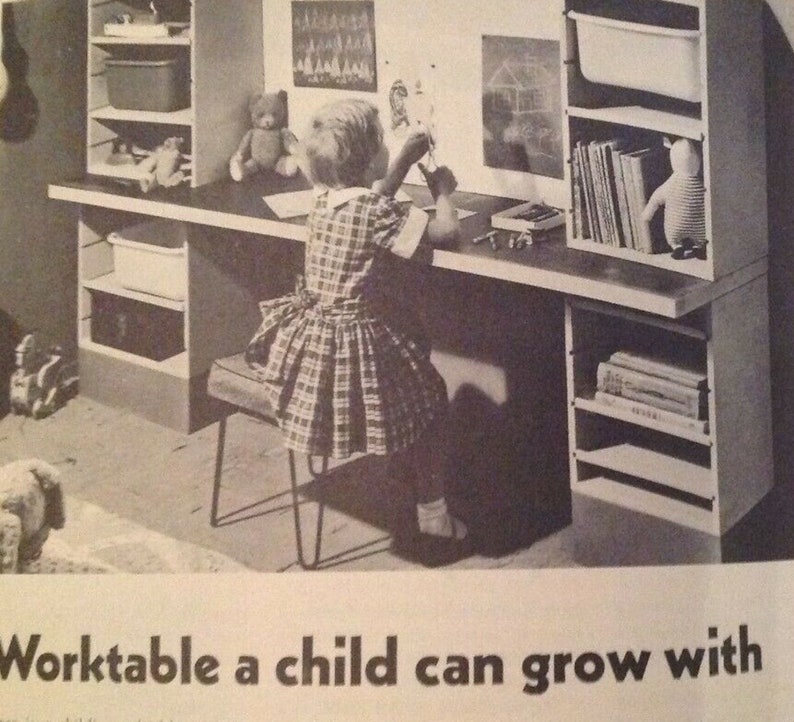 May include: A black and white photo of a child's desk and chair. The desk has shelves on either side and a child is sitting at the desk drawing. The caption reads "Worktable a child can grow with."