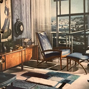 Puede incluir: Una sala de estar de estilo moderno de mediados de siglo con un sill&oacute;n y un reposapi&eacute;s azules, un armario de madera y una alfombra con un patr&oacute;n geom&eacute;trico. La habitaci&oacute;n tiene una gran ventana con vista al oc&eacute;ano.