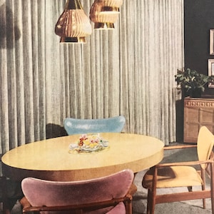 Puede incluir: Un comedor de estilo moderno de mediados de siglo con una mesa redonda de madera clara y cuatro sillas. Las sillas est&aacute;n tapizadas en tela rosa, azul y amarilla. Tres l&aacute;mparas colgantes doradas cuelgan del techo sobre la mesa.