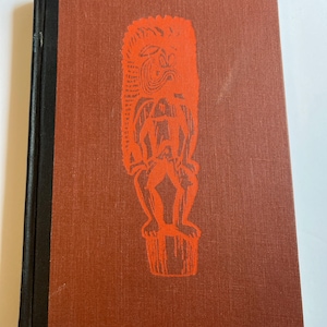 May include: A vintage hardback book with a rust-coloured cover and a black spine. The cover features a vibrant orange illustration of a stylized figure. The book's design suggests a focus on cultural or historical themes.