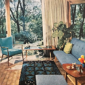 Puede incluir: Una sala de estar con un sof&aacute; azul, un sill&oacute;n azul, una mesa de caf&eacute;, un reposapi&eacute;s azul y una mesa auxiliar de madera. La habitaci&oacute;n tiene una ventana grande con cortinas y vista a los &aacute;rboles. Hay una alfombra en el suelo con un patr&oacute;n azul y negro.