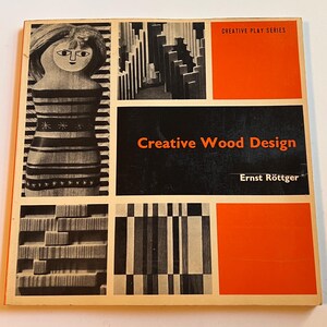Pode incluir: Livro vintage intitulado "Creative Wood Design" de Ernst Röttger. A capa apresenta um esquema de cores preto e laranja com desenhos geométricos de madeira e uma ilustração estilizada de uma boneca. Parte da "Creative Play Series".