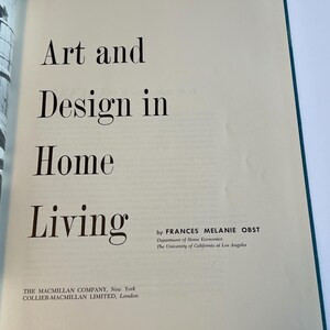 以下が含まれることがあります： 「Art and Design in Home Living」というタイトルが大きな黒い文字で書かれた開かれた本。著者であるフランシス・メラニー・オストの名前と出版社の情報も表示されています。ページはオフホワイトで、緑色の縁取りがあります。