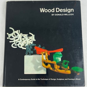 May include: Book cover with the title "Wood Design" by Donald Willcox. The cover features a colorful abstract sculpture made of wood.