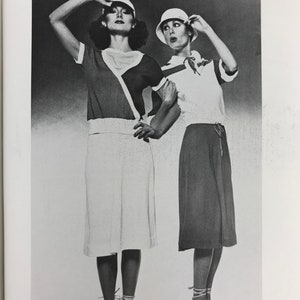 May include: Two women wearing white and black summer outfits with white shoes and hats. The text "Clovis Ruffin for Ruffinknit, Summer '76." is printed below the image.
