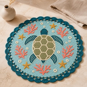 Op de afbeelding: Een rond gehaakt kleedje met een centrale zeeschildpad in groentinten, omringd door koraalkleurige zeewaaiers en gele zeesterren op een lichtblauwe achtergrond. Het werk is afgewerkt met een donkergroene, geschulpte gehaakte rand.