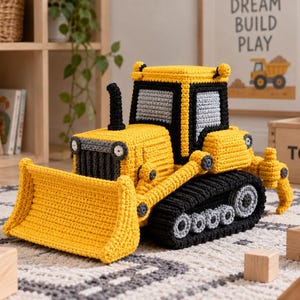 May include: A yellow, black, and gray crocheted bulldozer toy featuring a front blade, a cab with gray windows, a black exhaust pipe, and black tracks with gray wheels. The construction vehicle is crafted with visible yarn stitches.