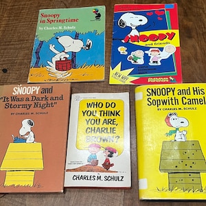 Peut inclure: Un ensemble de cinq livres Peanuts mettant en scène Snoopy et Charlie Brown. Les titres incluent Snoopy in Springtime, Snoopy and Friends, It Was a Dark and Stormy Night, Who Do You Think You Are, Charlie Brown? et Snoopy and His Sopwith Camel.