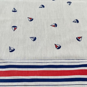 May include: A white fabric featuring a repeating pattern of small sailboats in navy blue and red. The lower section of the fabric displays a horizontal border consisting of alternating thick red stripes and thinner navy blue stripes on a white background.