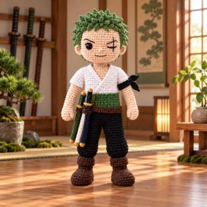 May include: A crocheted doll featuring a character with short green hair, a scar over one eye, and a white V-neck shirt. The doll wears a green sash, black trousers, and brown boots, with three miniature swords attached to the waist and a black band on one arm.