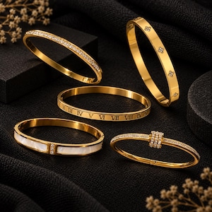 Può includere: Una collezione di cinque bracciali rigidi in metallo color oro. Uno presenta una fila di pietre chiare, un altro ha motivi floreali a quattro petali, uno mostra numeri romani, uno contiene segmenti a intarsio bianco e l'ultimo ha una fascia centrale di pietre chiare.