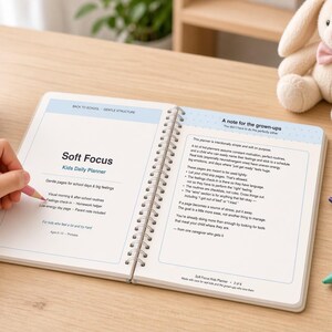 Könnte beinhalten: Ein spiralgebundener Soft Focus Kids Daily Planner, der auf einer Seite mit der Überschrift A note for the grown-ups aufgeschlagen ist. Der Planer hat weiße Seiten mit blauem Text und Überschriften. Ein rosa Stift liegt auf der linken Seite.