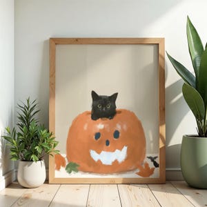 Peut inclure: Une impression d'art encadrée représentant un chat noir assis à l'intérieur d'une grande citrouille orange peinte à la main, avec un visage sculpté en blanc. L'œuvre est sur un fond beige neutre, illustrant un thème festif d'automne.