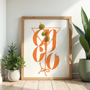 Peut inclure: Une impression d'art encadrée présentant un grand graphique orange stylisé d'un verre à martini avec trois olives vertes sur un cure-dent. Le design intègre une typographie orange audacieuse et superposée formant la silhouette du verre.